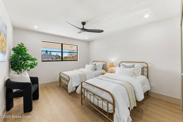 a bedroom with two beds and a potted plant