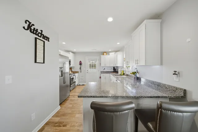 a kitchen with granite countertop white cabinets white appliances and sink