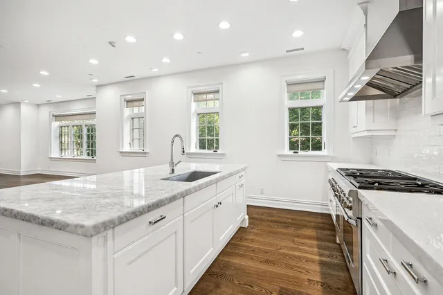 a kitchen with granite countertop kitchen island a stove a sink and wooden cabinets