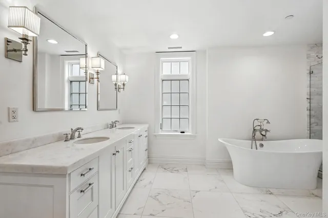 a bathroom with a tub a sink and mirror
