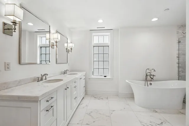 a bathroom with a tub a sink and mirror