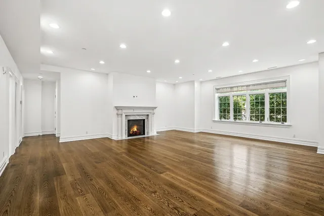 a view of empty room with wooden floor and fireplace