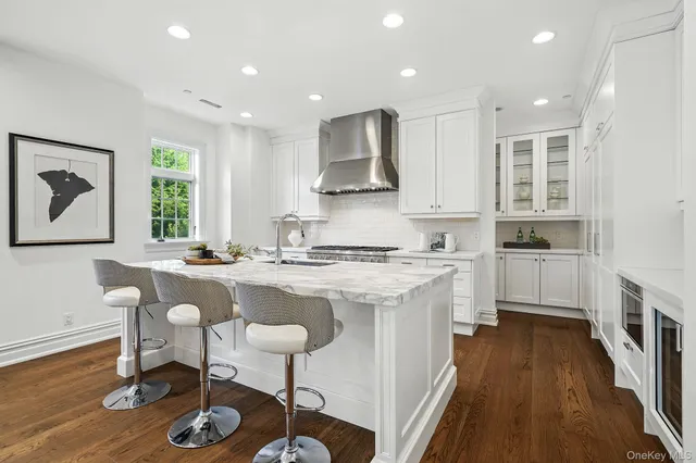 a kitchen with stainless steel appliances granite countertop a stove top oven a sink dishwasher a dining table and chairs with wooden floor