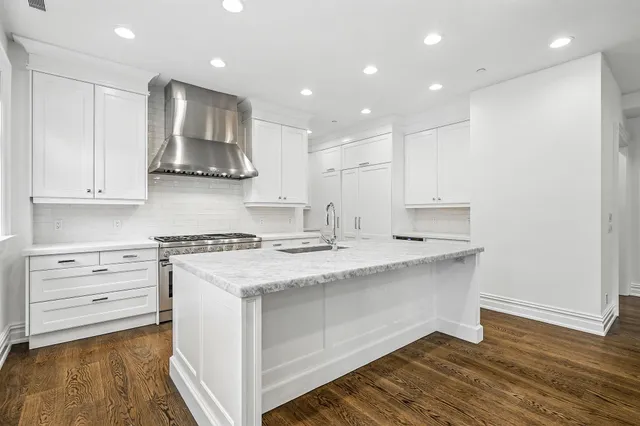 a kitchen with kitchen island white cabinets and stainless steel appliances