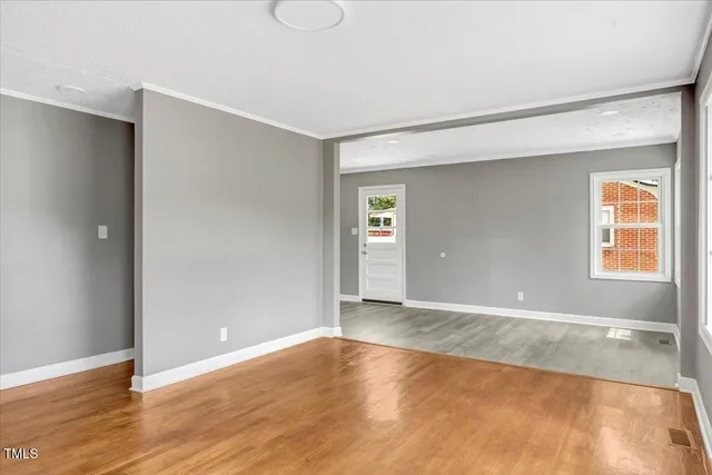 a view of an empty room with wooden floor and a window