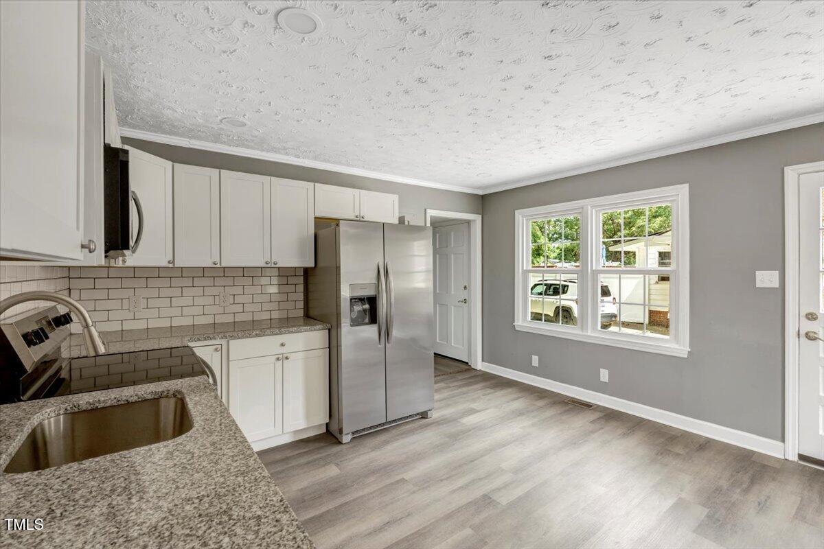 712 East 13th Street Roanoke Rapids, NC 27870 - Photo 19 of 46 a kitchen with a refrigerator sink and wooden cabinets