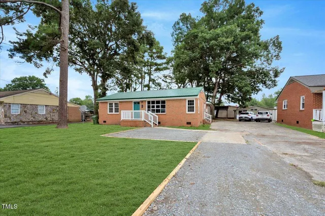 a front view of a house with a garden and tree