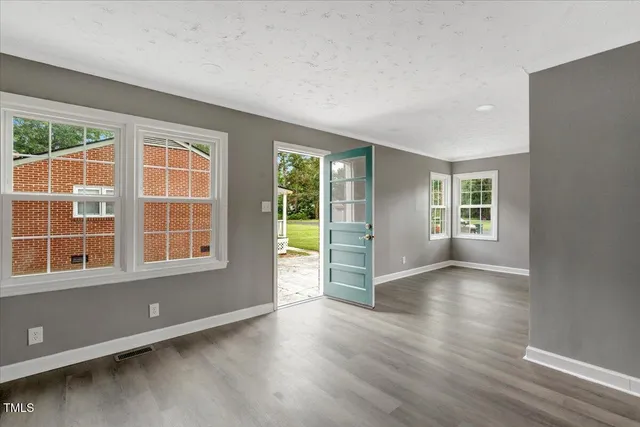 an empty room with wooden floor and windows