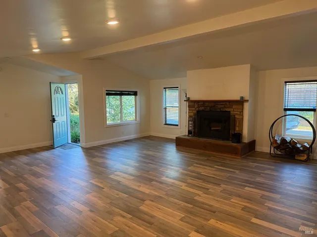 an empty room with hard wood floors and a fireplace