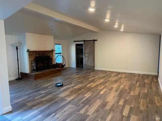 an empty room with wooden floor fireplace and windows