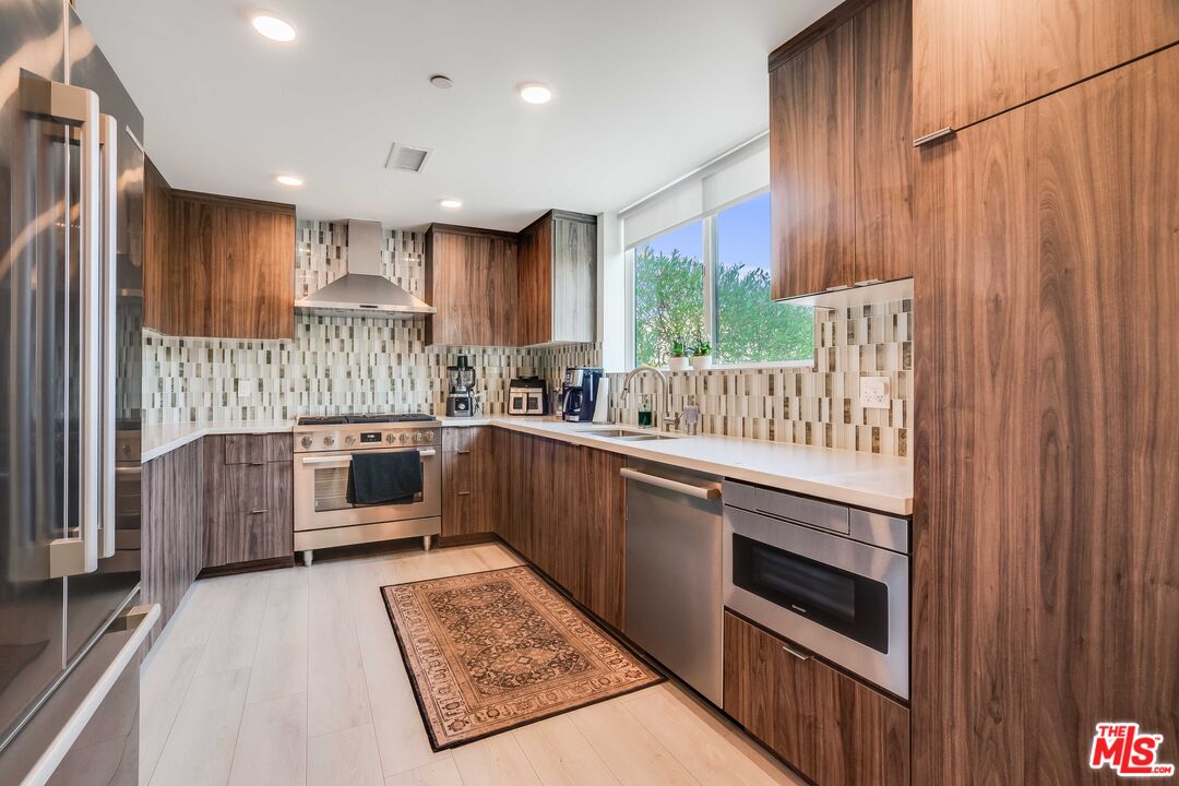 1021 South Shenandoah Street, Unit 101 Los Angeles, CA 90035 - Photo 6 of 18 a kitchen with kitchen island granite countertop wooden cabinets a sink and a stove