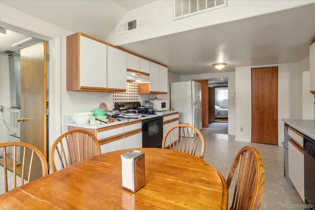 a kitchen with stainless steel appliances granite countertop a stove top oven a sink a dining table and chairs with wooden floor