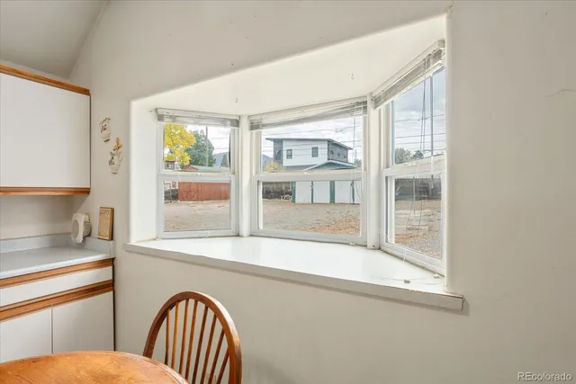a view of a hallway with a large window and kitchen view