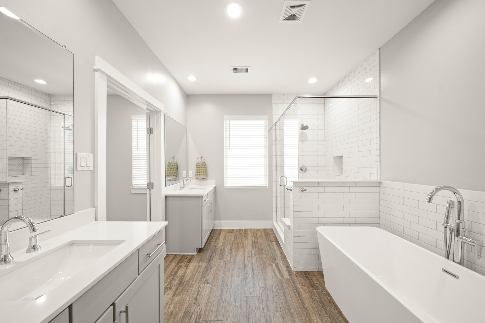 720 West Donovan Street Houston, TX 77091 - Photo 25 of 42 Luxury awaits you in this private bath complete with hardwood-like tile floors, dual dressing areas with painted Shaker-style cabinets, quartz counter tops and under-mount sinks accompanied by wall mounted mirrors.