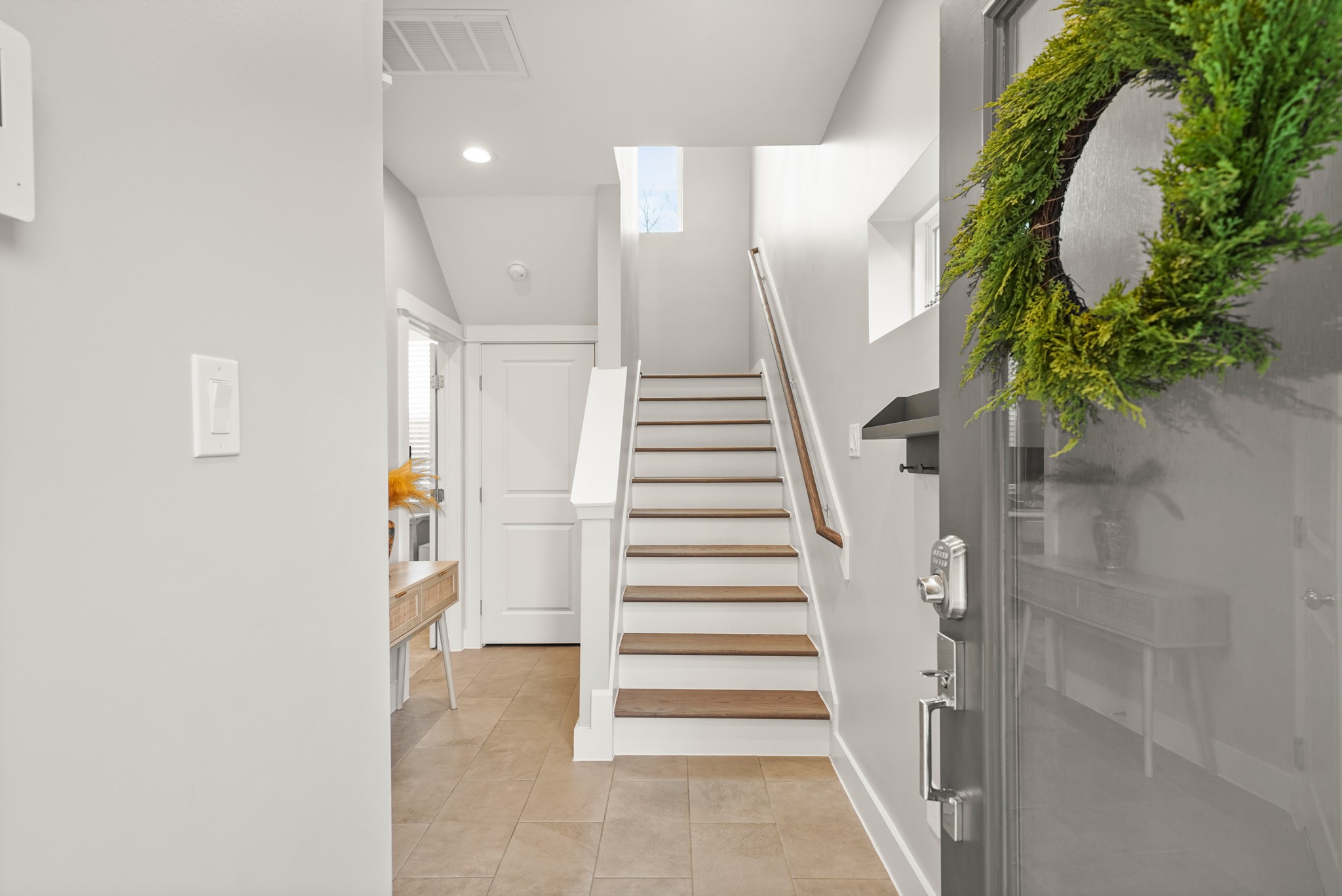 720 West Donovan Street Houston, TX 77091 - Photo 3 of 42 The foyer of the home with high ceiling, 12"x24" tile floor and recessed lighting opens to a staircase with hardwood treads leading to the second level of the home. The door in the background to the left leads to the 3rd bedroom of the home.