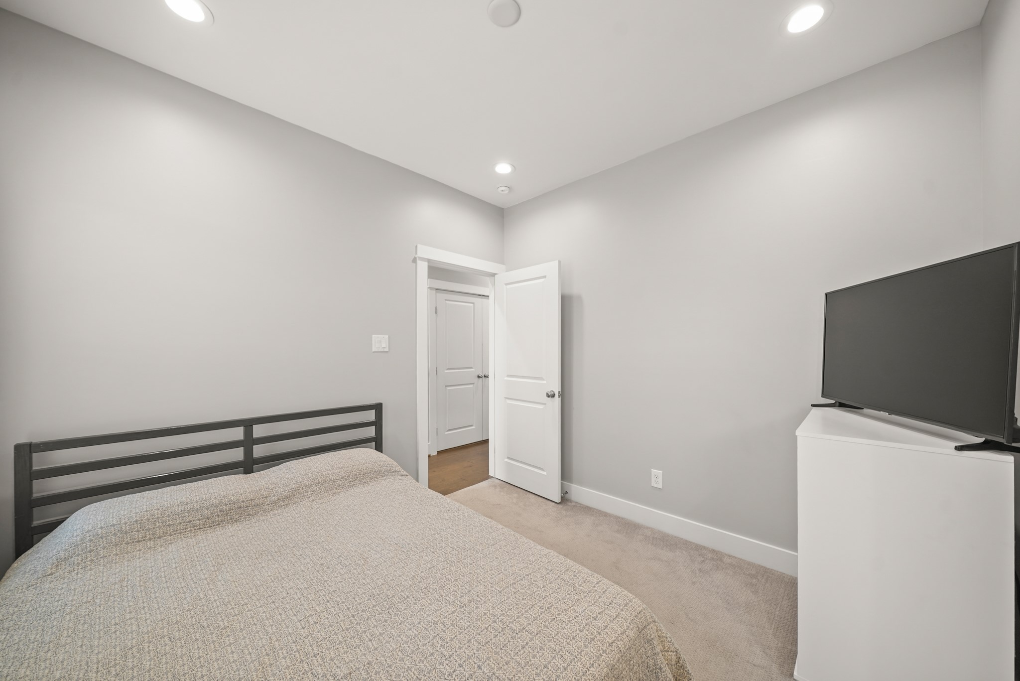 720 West Donovan Street Houston, TX 77091 - Photo 31 of 42 Neutral tones define the second bedroom with the third floor corridor and access to the utility room in the background.
