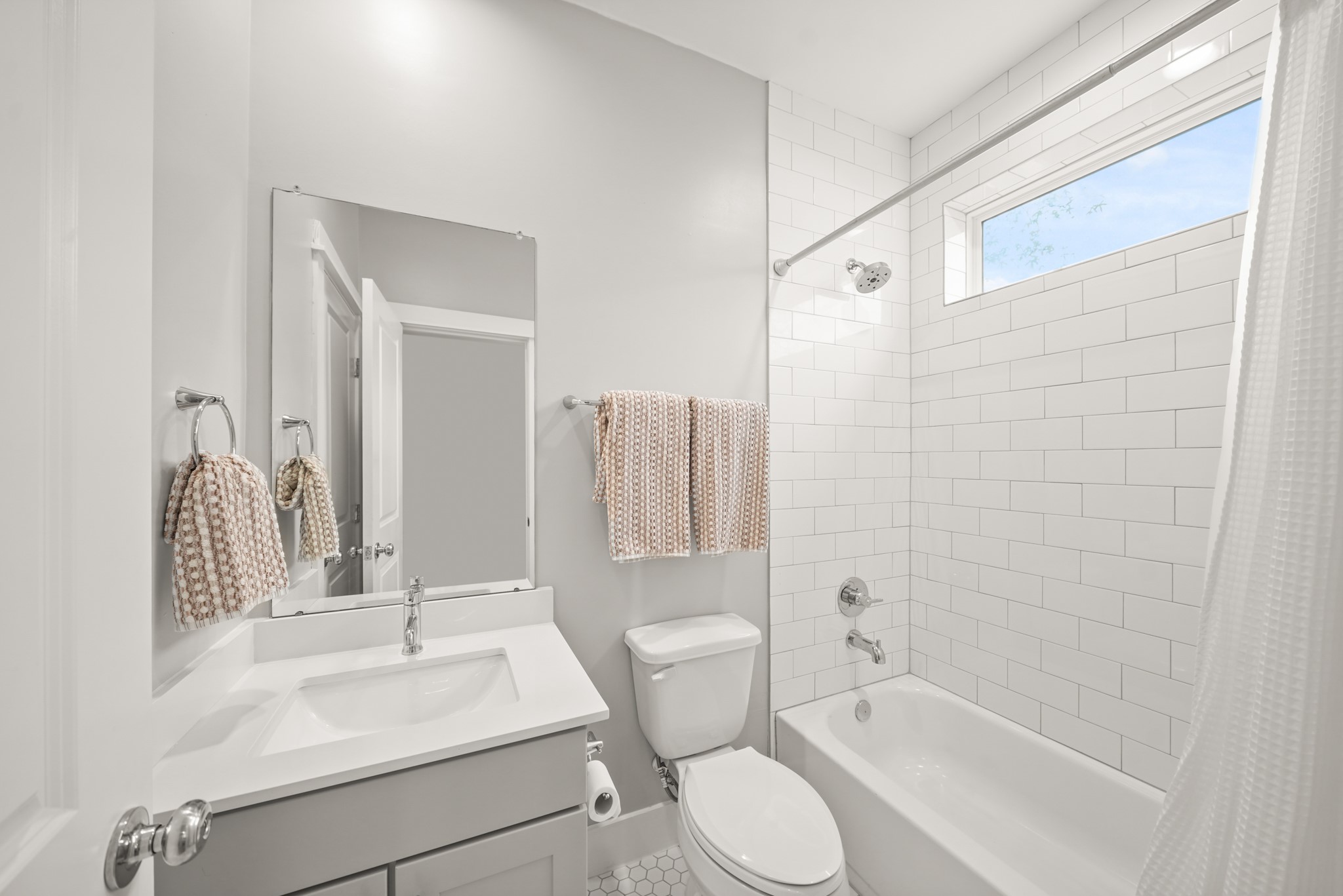720 West Donovan Street Houston, TX 77091 - Photo 33 of 42 Serving as the home's third full bath, this ensuite bath has painted Shaker-style cabinets with quartz counter top & integrated back splash, wall mounted mirror with recessed lighting above, a subway tile surrounded combination with tub/shower with a fixed glass window above and hexagonal tile flooring.
