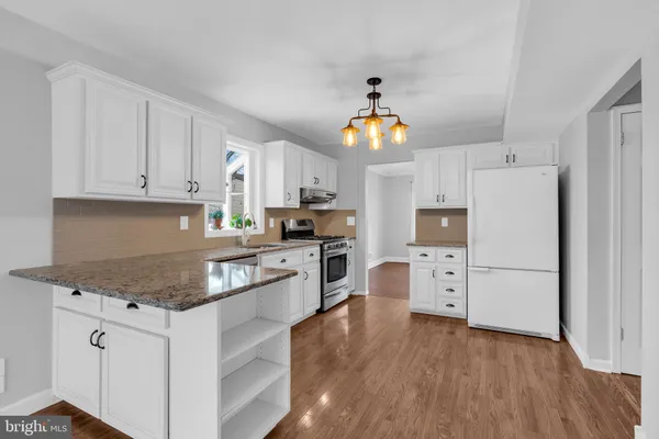 a kitchen with granite countertop a refrigerator a stove cabinets and wooden floor