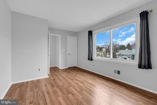 a view of an empty room with a window and wooden floor