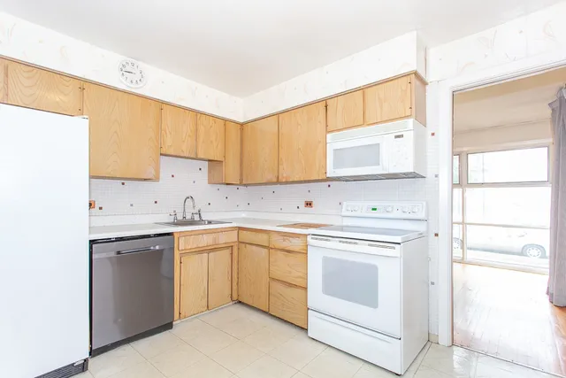 a kitchen with white cabinets appliances a sink and a window