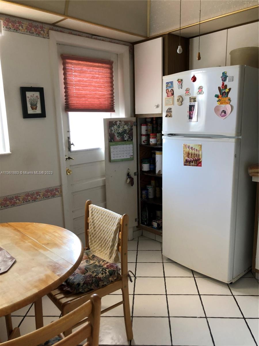 Royal Oaks Miami, FL 33179 - Photo 9 of 18 a white kitchen with a refrigerator a table and chairs in it
