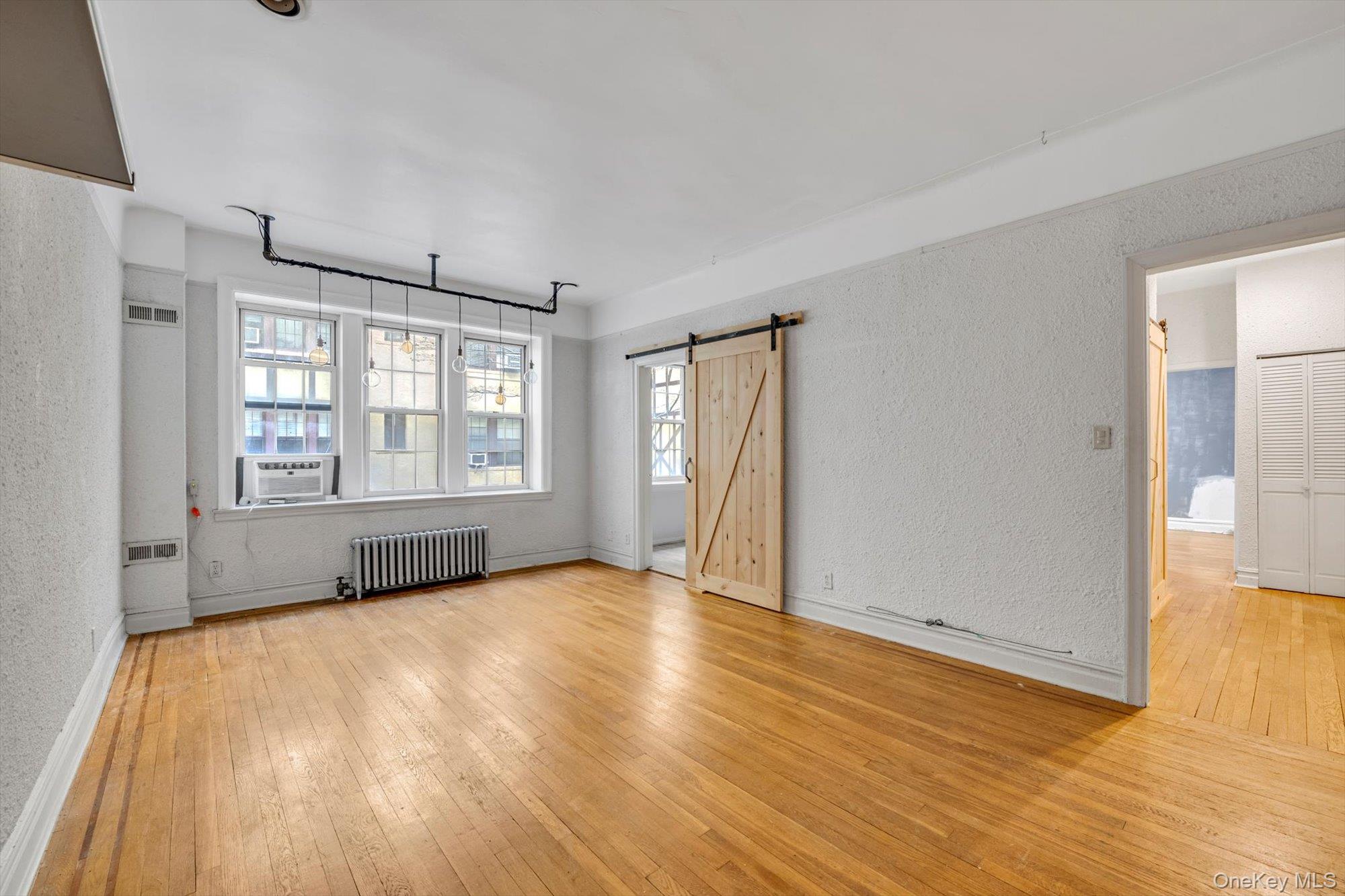 4 Maple Drive, Unit 1J Great Neck, NY 11021 - Photo 7 of 15 an empty room with wooden floor and windows