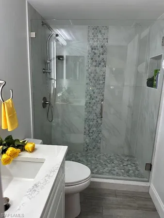 a bathroom with a granite countertop sink a toilet and shower
