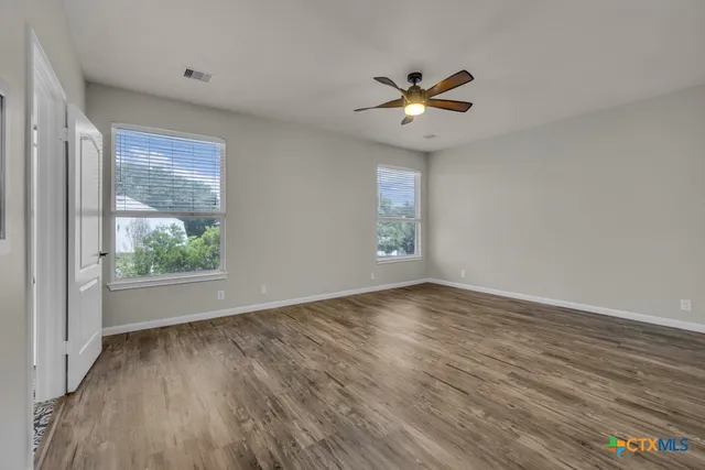 a view of an empty room with a window and wooden floor