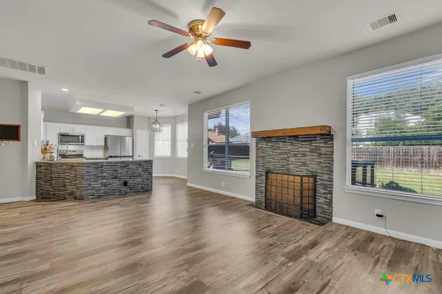 a view of an empty room with a kitchen and a window