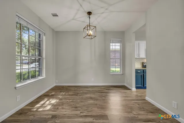 a dining room with wooden floor and a chandelier