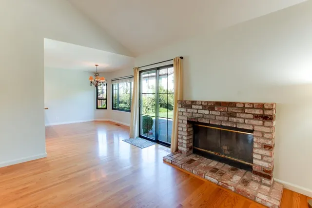 an empty room with wooden floor fireplace and windows