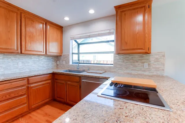 a kitchen with stainless steel appliances granite countertop wooden cabinets a sink and a window