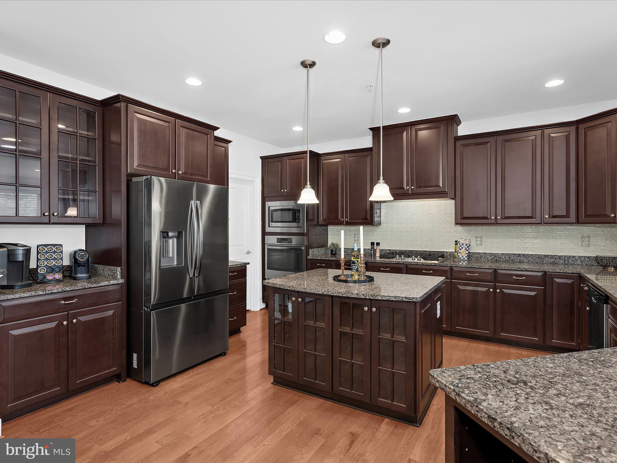 13801 Racetrack Field Court Bowie, MD 20720 - Photo 21 of 66 a kitchen with kitchen island granite countertop wooden cabinets and a stainless steel appliances