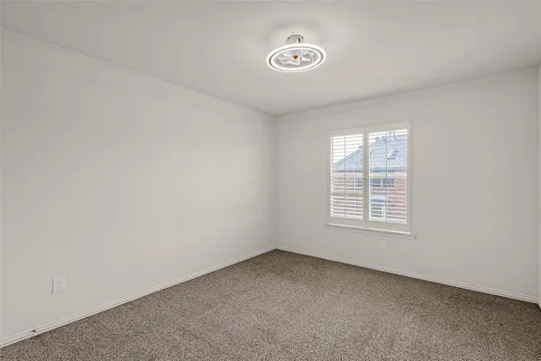 an empty room with chandelier fan and windows