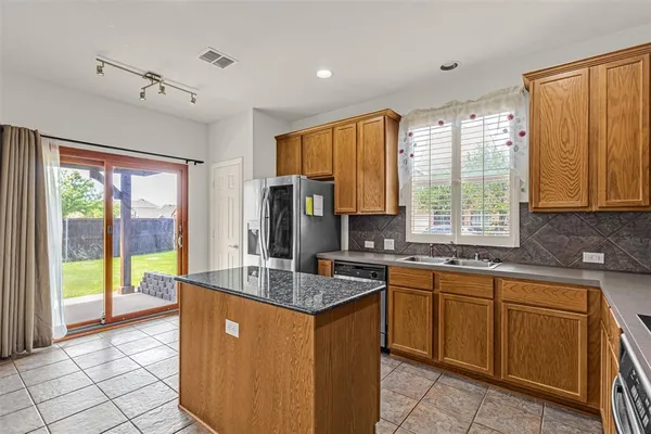 a kitchen with granite countertop a refrigerator and a stove top oven