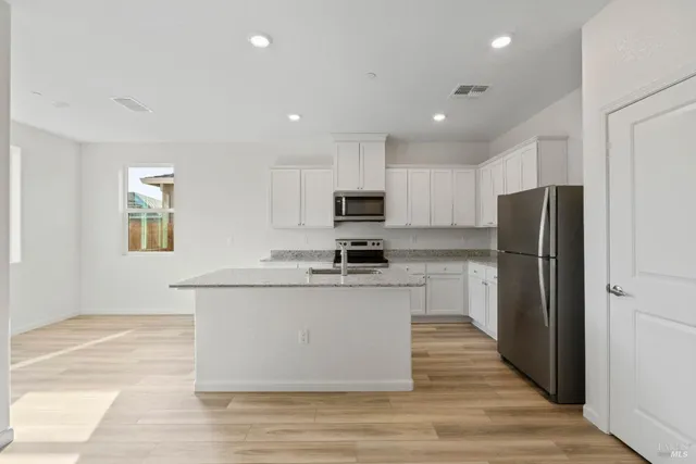 a kitchen with stainless steel appliances granite countertop a refrigerator stove top oven and sink