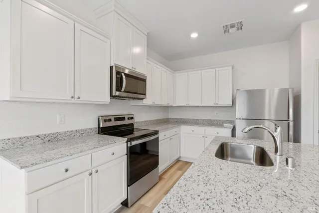 a kitchen with stainless steel appliances granite countertop a sink stove top oven and refrigerator
