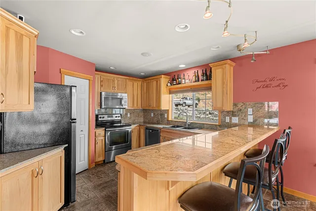 a kitchen with stainless steel appliances kitchen island granite countertop a table chairs in it and wooden floors