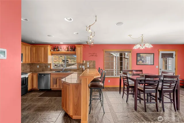 a kitchen with stainless steel appliances granite countertop a stove top oven a dining table and chairs with wooden floor