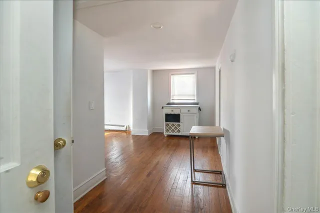 an empty room with wooden floor fireplace and windows