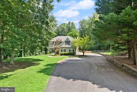 a view of a house next to a yard with big trees