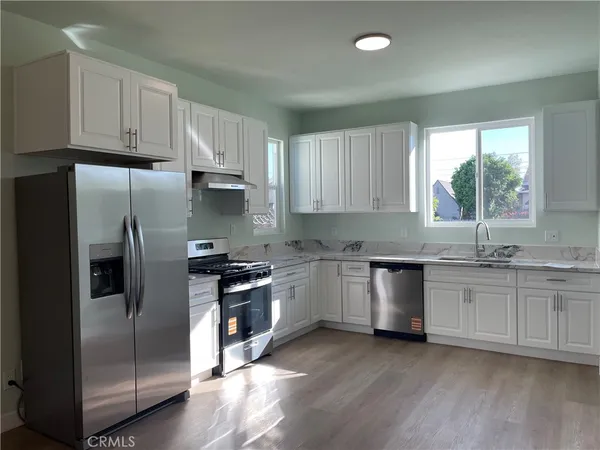 a kitchen with refrigerator and wooden floor