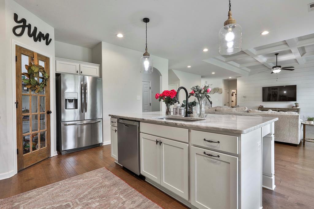 169 Hart Ridge Court Fortson, GA 31808 - Photo 23 of 50 a kitchen with stainless steel appliances granite countertop a refrigerator a sink dishwasher a oven and a dining table with wooden floor