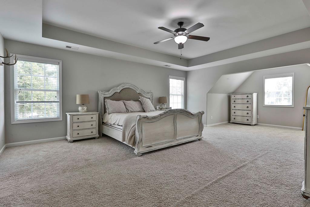 169 Hart Ridge Court Fortson, GA 31808 - Photo 29 of 50 a spacious bedroom with a bed a chandelier and a window