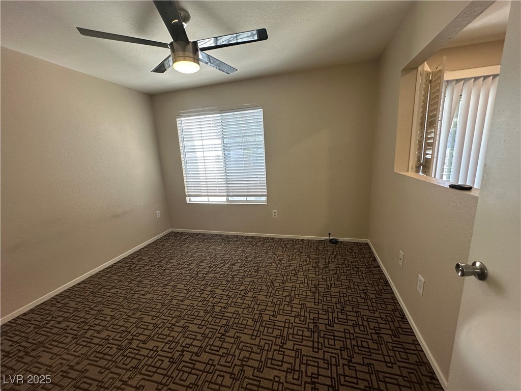 1908 High Valley Court, Unit 204 Las Vegas, NV 89128 - Photo 12 of 18 Empty room with dark carpet, a ceiling fan, and a textured wall