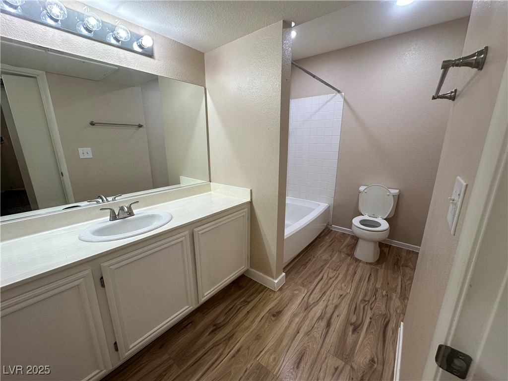 1908 High Valley Court, Unit 204 Las Vegas, NV 89128 - Photo 14 of 18 Full bathroom with dark wood finished floors, shower / bathtub combination, vanity, a textured ceiling, and a textured wall