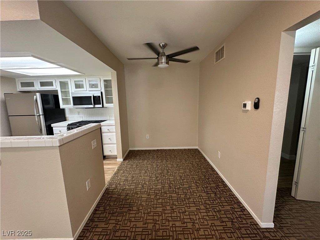 1908 High Valley Court, Unit 204 Las Vegas, NV 89128 - Photo 15 of 18 Kitchen featuring white cabinets, appliances with stainless steel finishes, glass insert cabinets, ceiling fan, and tile counters