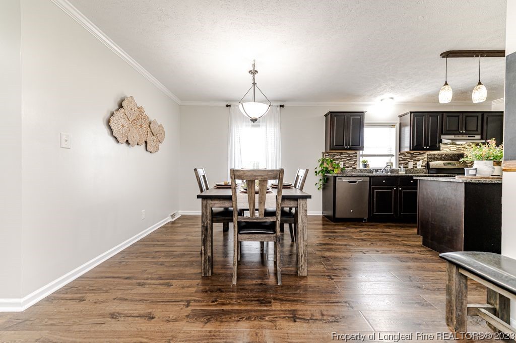 125 Wright Road Vass, NC 28394 - Photo 18 of 48 a dining room with wooden floor a chandelier a wooden table and chairs