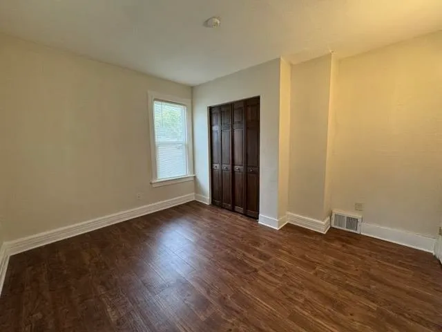 an empty room with wooden floor and windows