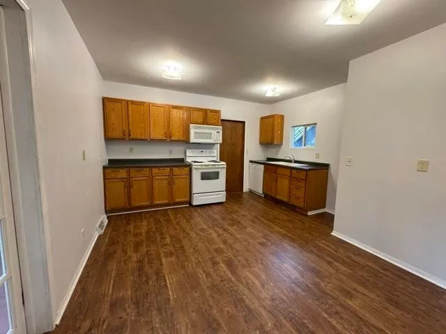 a view of kitchen with stainless steel appliances granite countertop a stove and a wooden floors